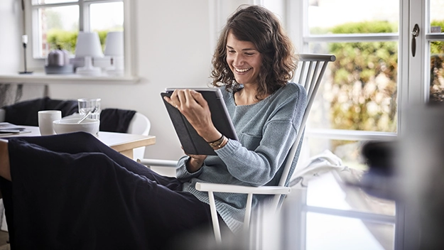 Relaxed young woman sitting at table using tablet
