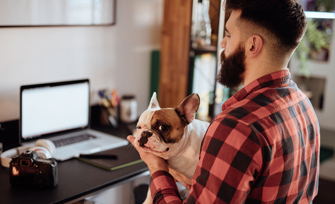 Man holding his dog and working from home office